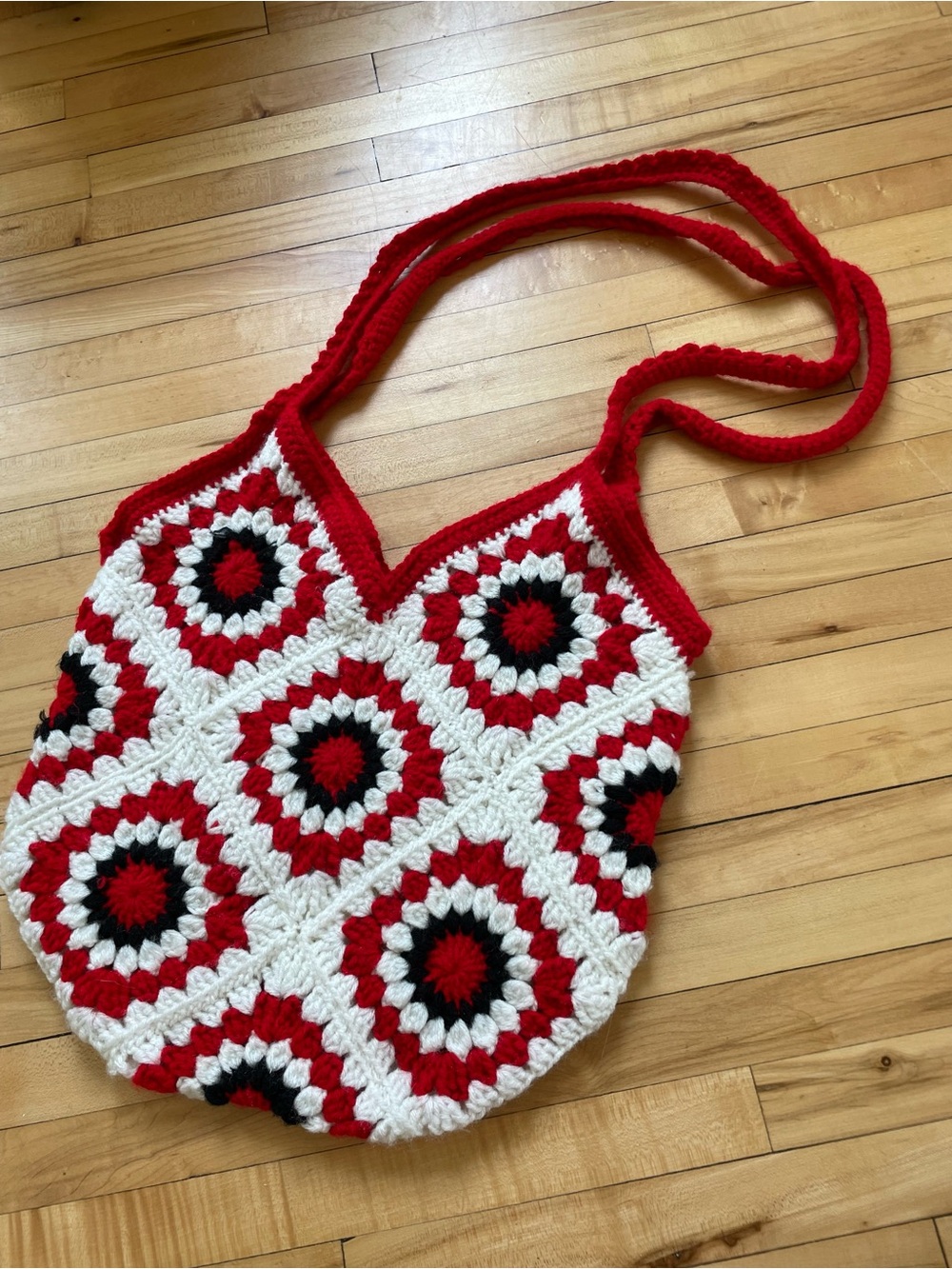 Handmade crochet bag with red, white, and black hexagonal granny square pattern.
